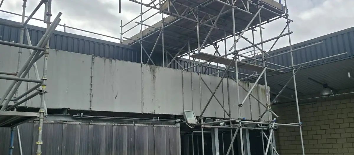 Scaffold rising over a single-storey bay to a beamed platform on an industrial building