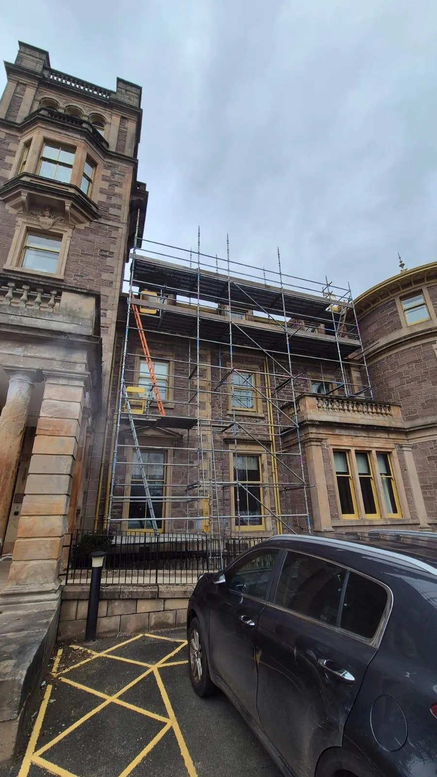 Scaffolding to roof level on an ornate red sandstone building