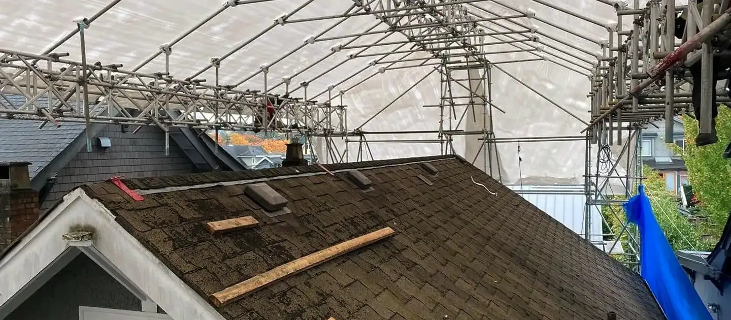 Sheeted temporary roof above a tiled house roof, seen from the platform