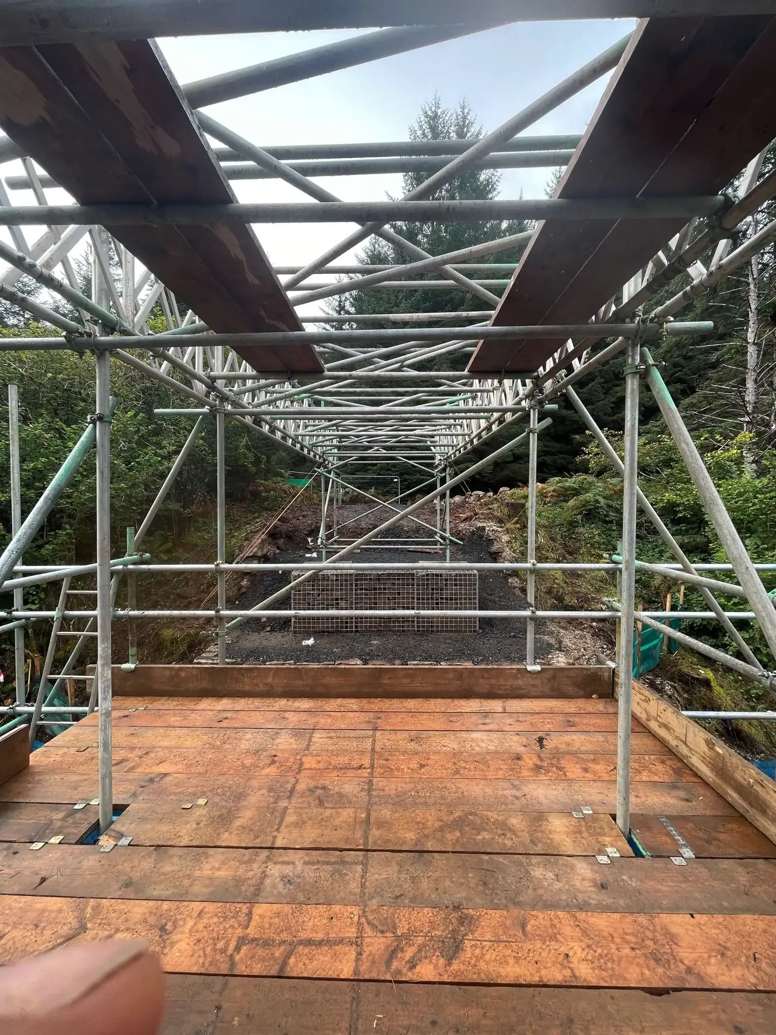 Access bridge with a boarded deck and handrails spanning between stone walls