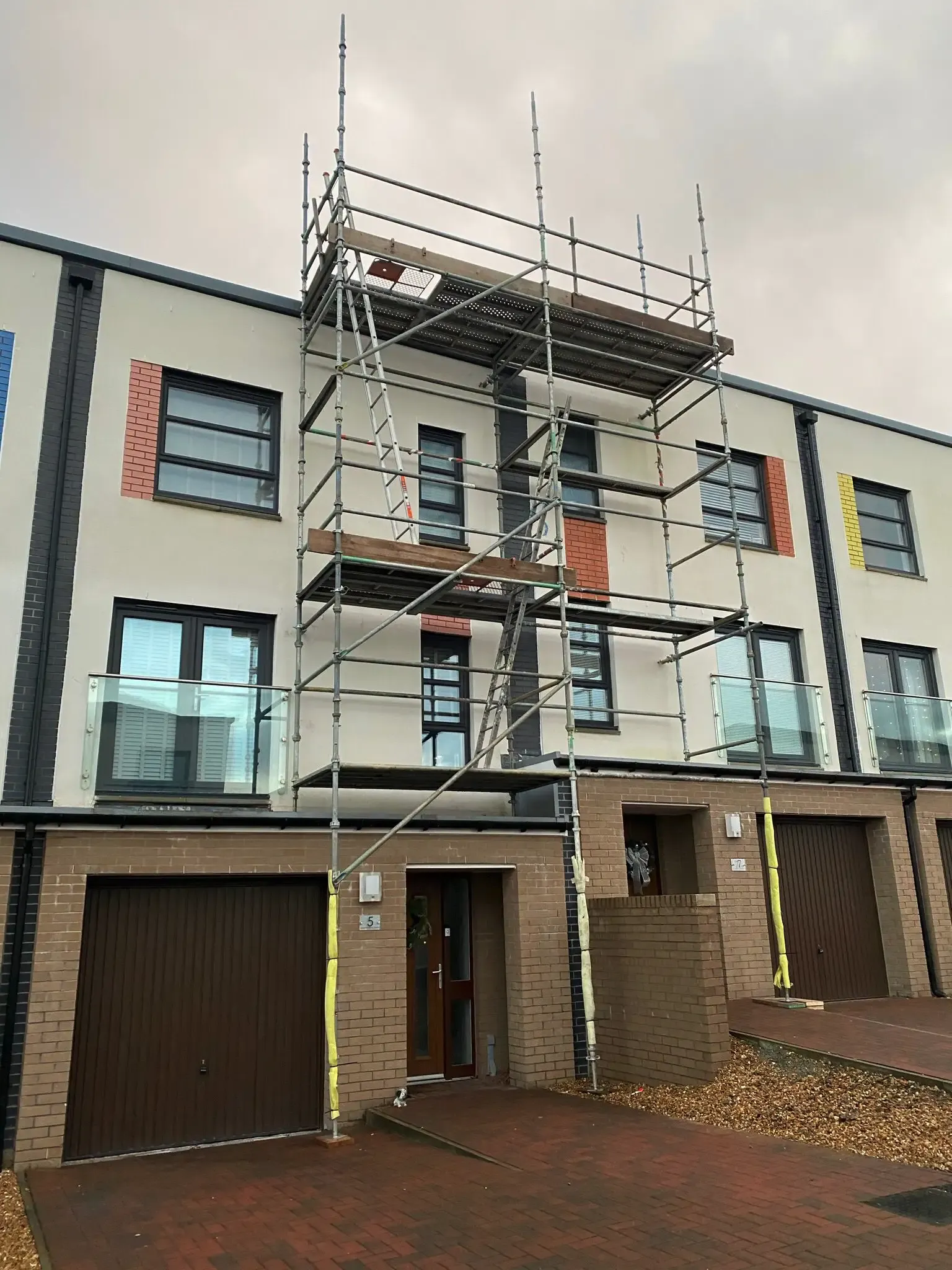 Scaffolding erected against a modern three-storey townhouse
