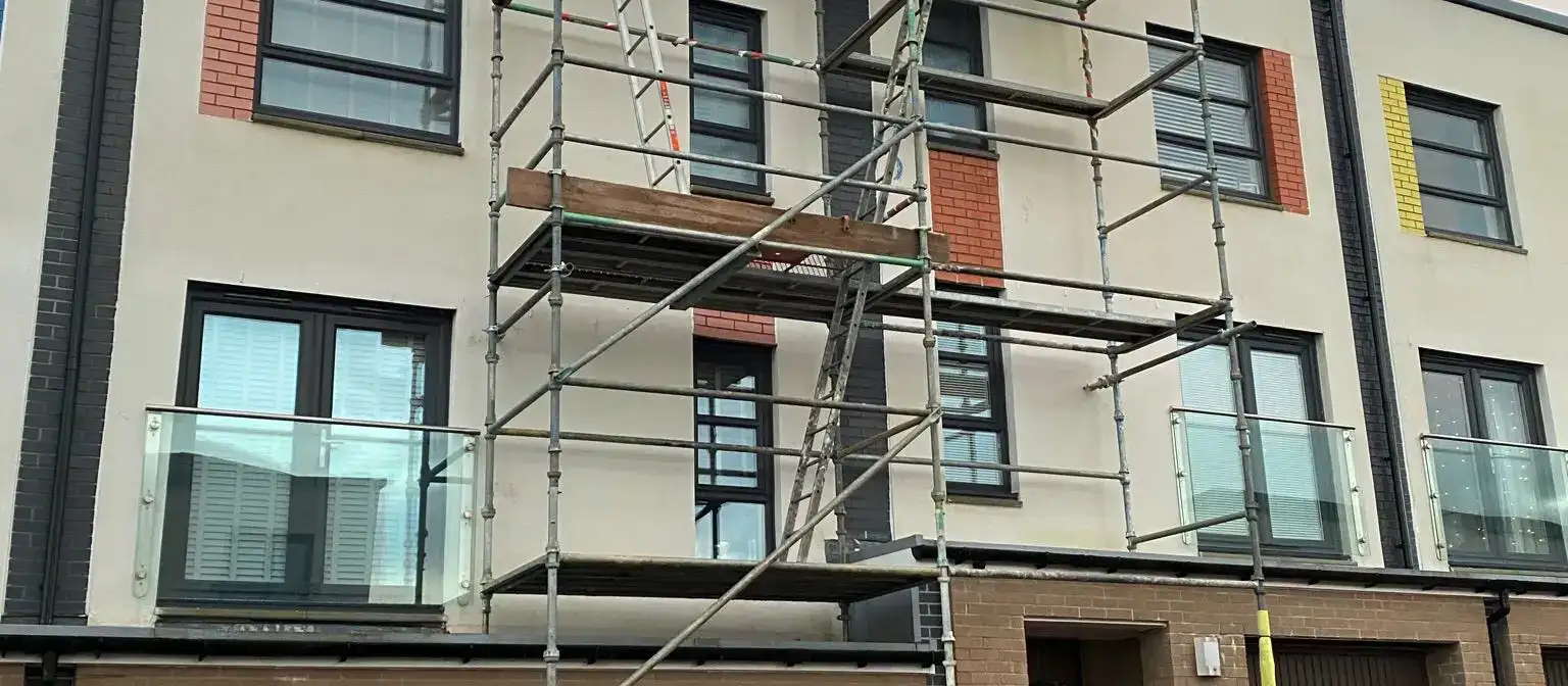 Scaffolding erected against a modern three-storey townhouse