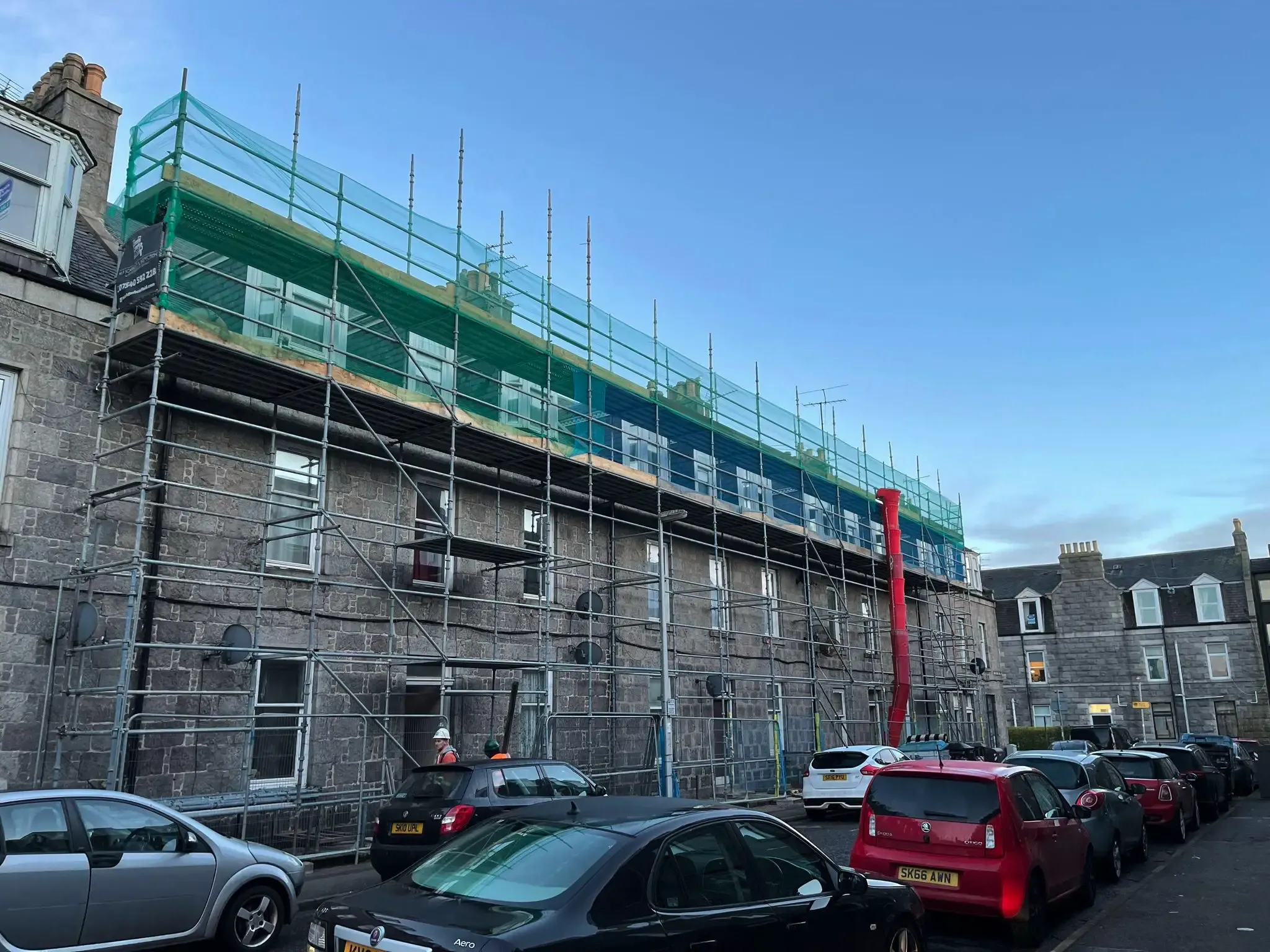 Scaffolding with debris netting along the full length of a stone terrace