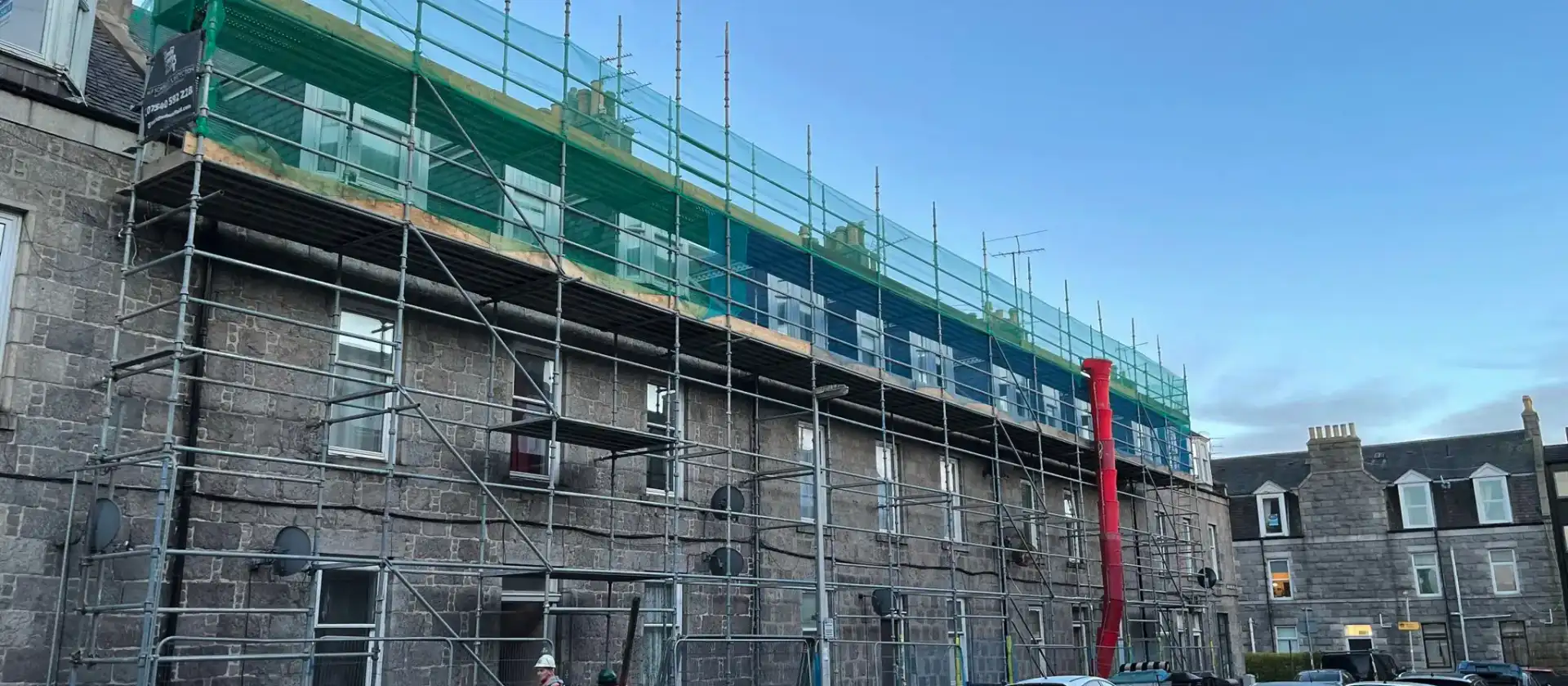 Scaffolding with debris netting along the full length of a stone terrace