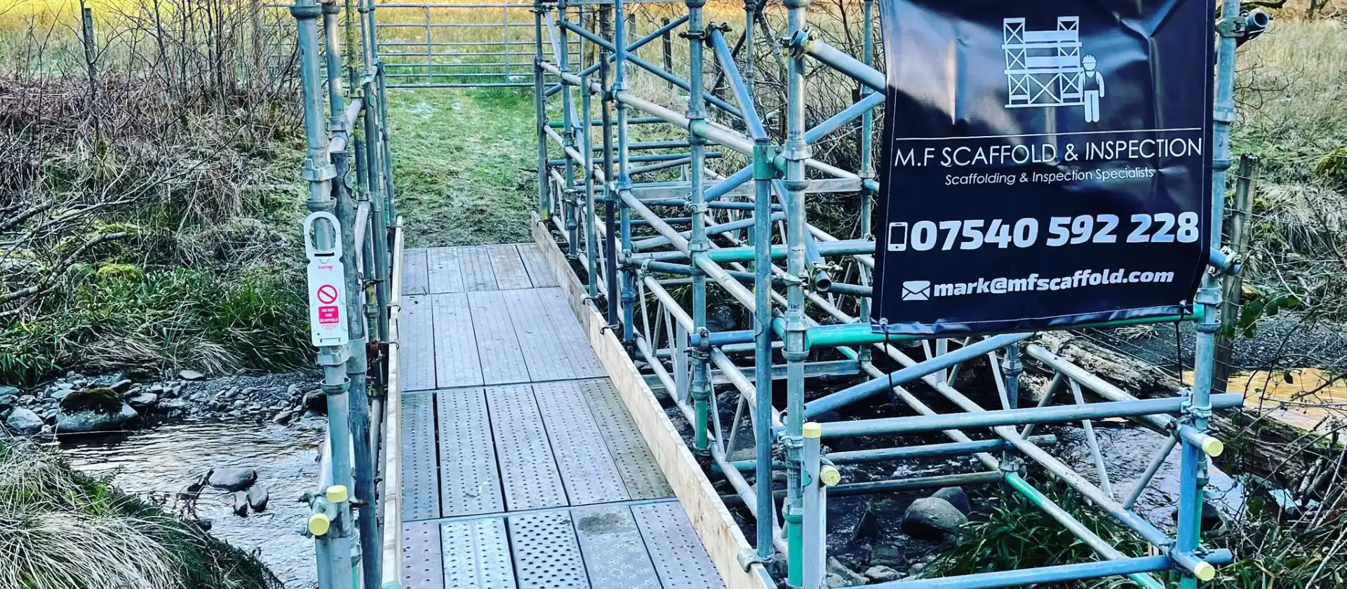 Scaffold access bridge with a boarded walkway over rough ground