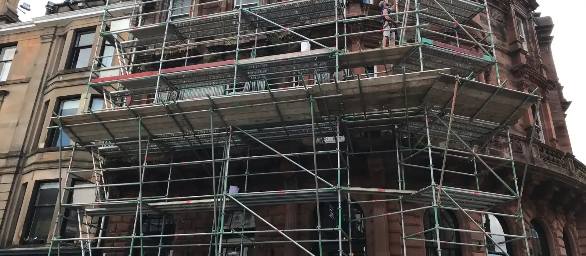 Scaffolding around the upper floors of a red sandstone building
