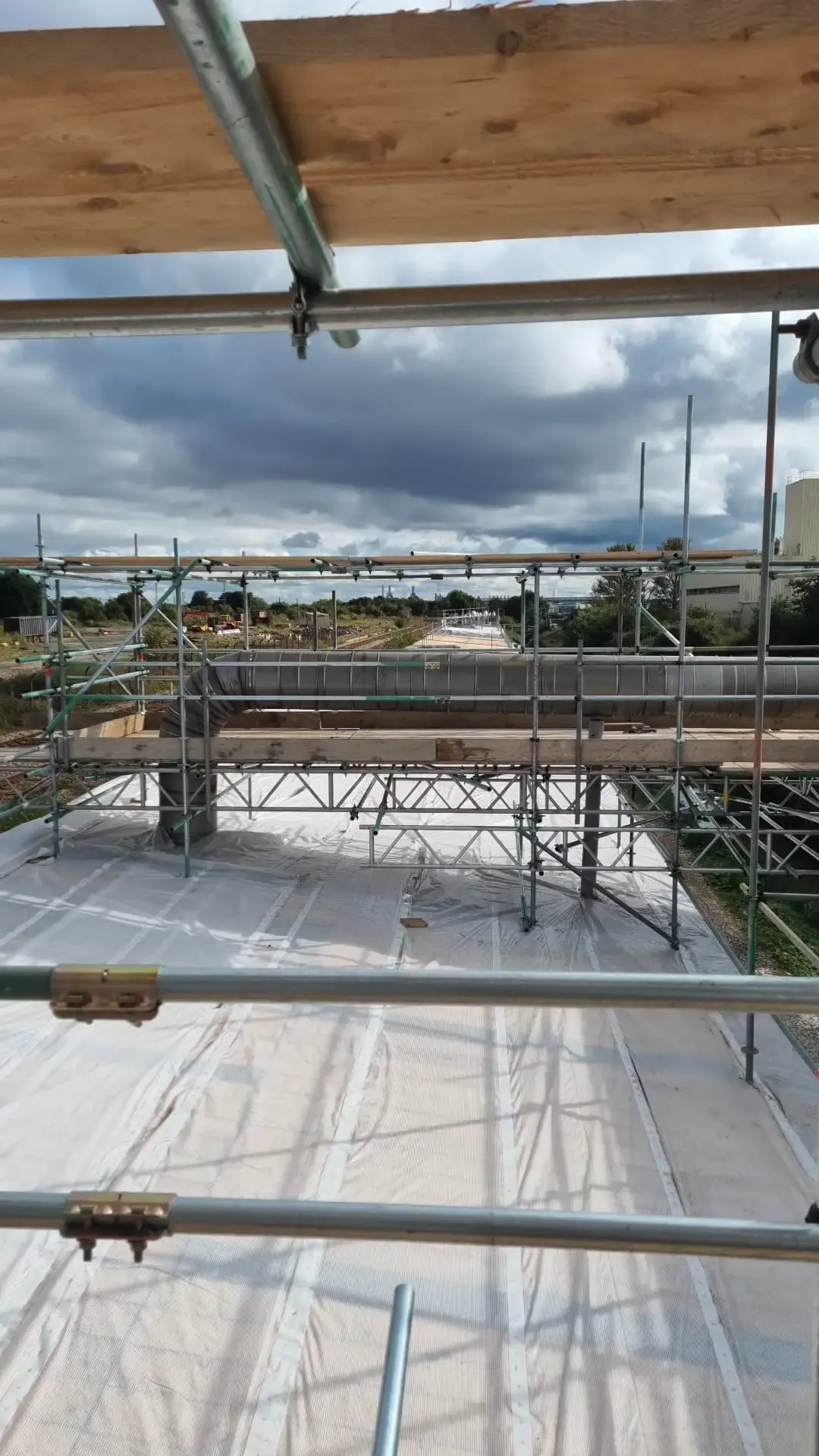 View along a long sheeted structure from the top of a scaffold