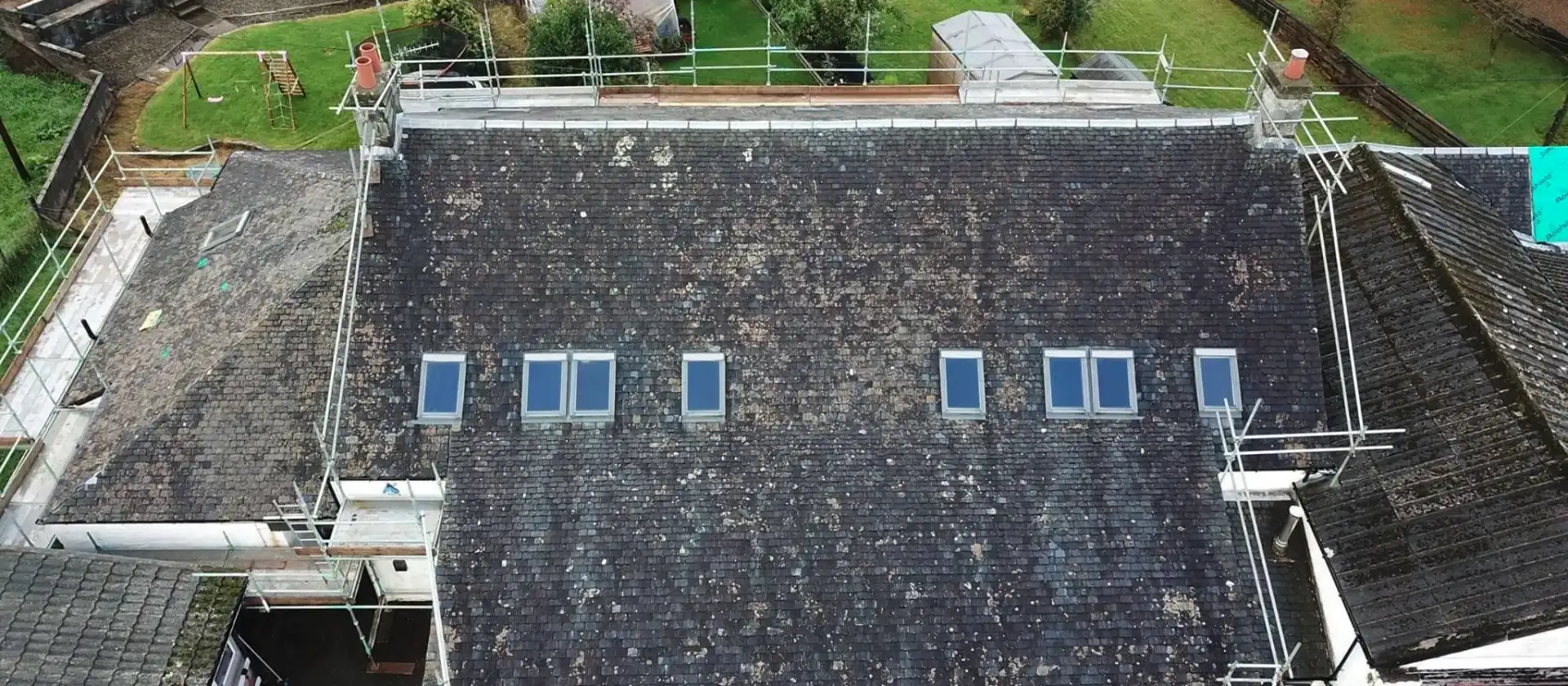 Aerial view of roof-level scaffolding around a slate roof