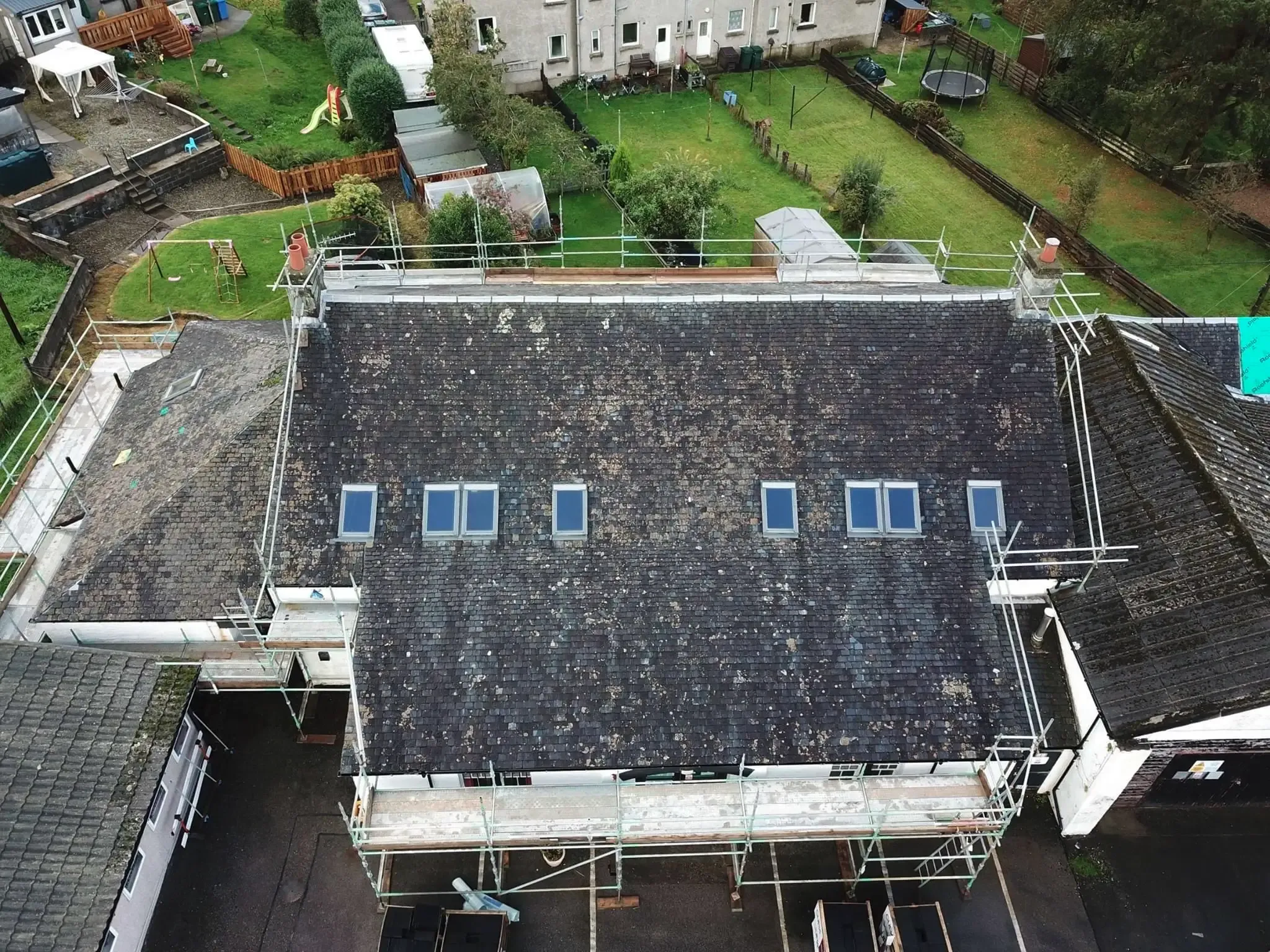 Aerial view of roof-level scaffolding around a slate roof