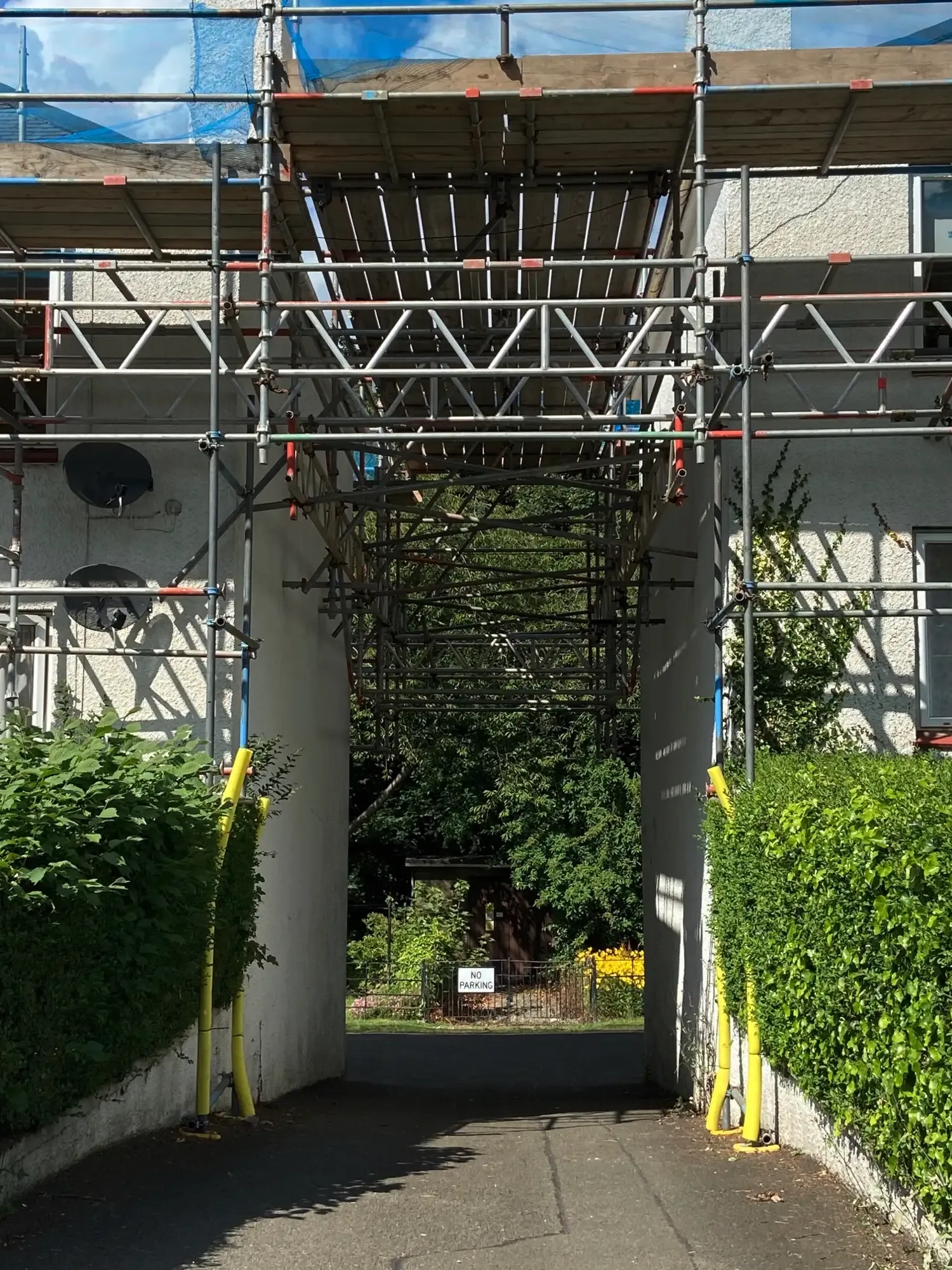 Scaffold spanning a pathway between two buildings, keeping the route open below