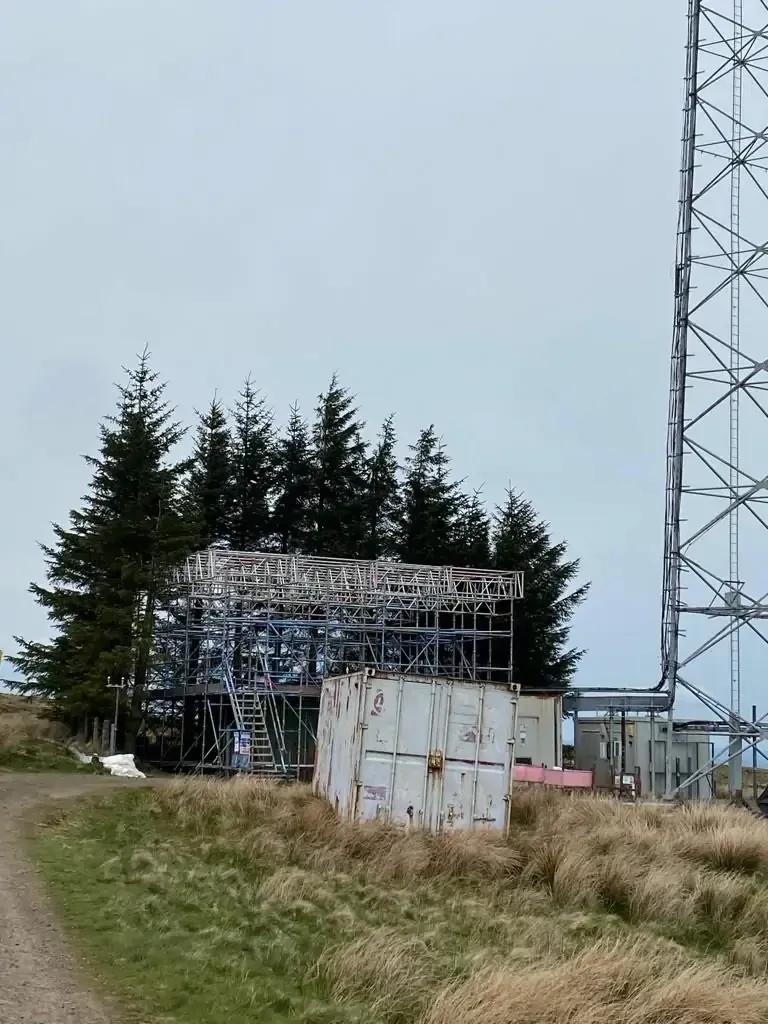 Scaffold structure beside a lattice mast on an exposed hilltop