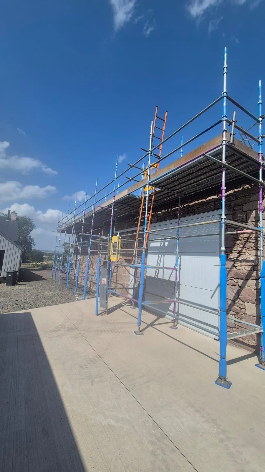 Roof-level scaffolding along a single-storey stone building