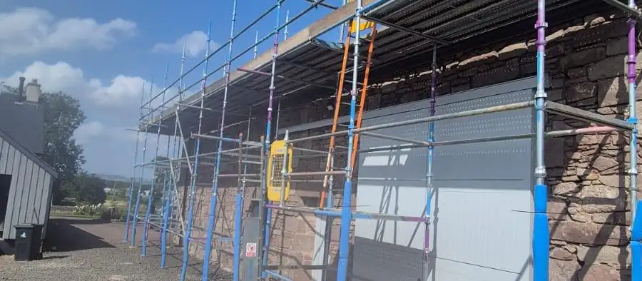 Roof-level scaffolding along a single-storey stone building